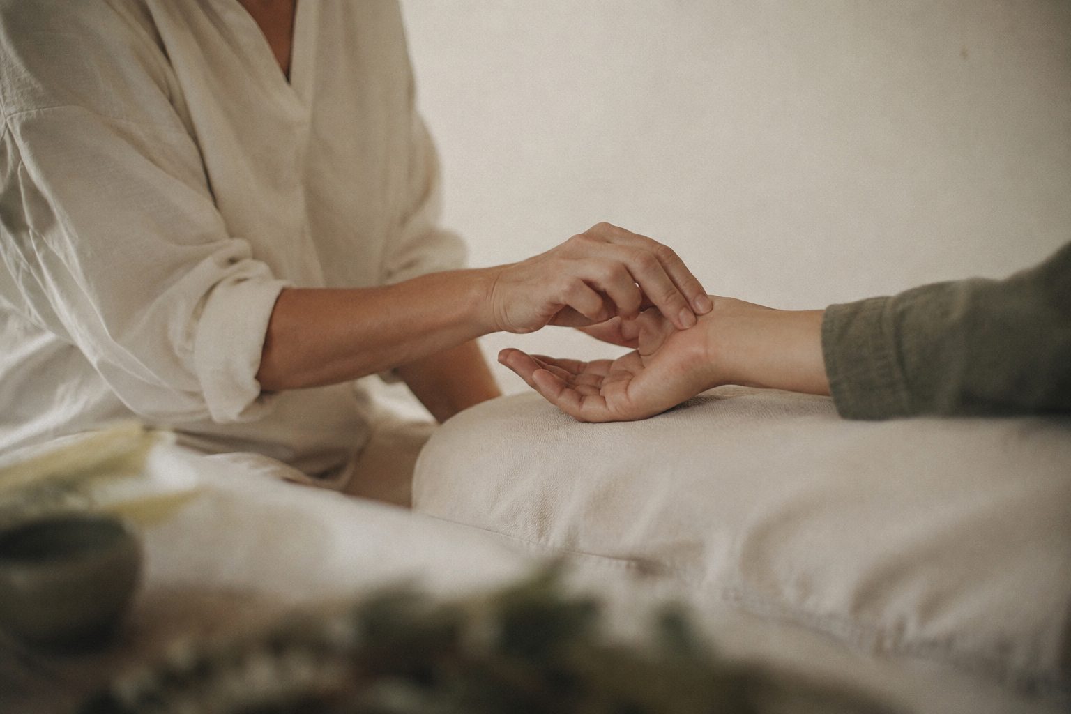 A practitioner's hands gently taking a client's wrist